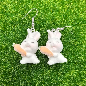 Cute white flocked bunny earrings with carrot charm on natural green grass background