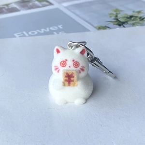 Macro detail of white flocked cat keychain with coin eyes and gold currency plaque