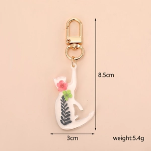 Detail view of resin cat keychain with red and green dried flowers and gold metal clasp