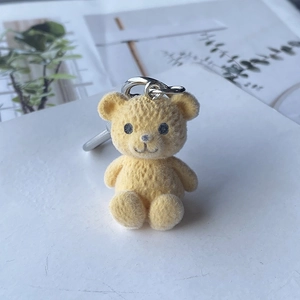 Gros plan du porte-clés ours jaune floqué avec texture velours et anneau en métal argenté