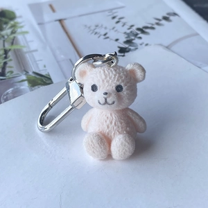 Gros plan d'un porte-clés ours rose floqué avec fermoir en argent et texture douce