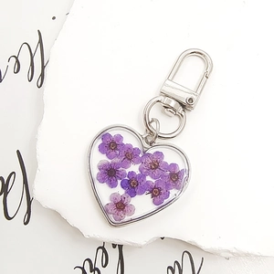 Macro shot of heart-shaped pendant with purple dried flowers and silver lobster clasp