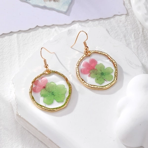 Detailed macro view of resin-filled gold ring earrings with natural dried flower petals