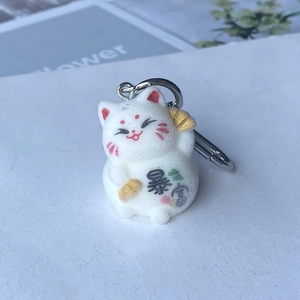 Macro detail of a white flocked lucky cat keychain with Baofu text and silver hook