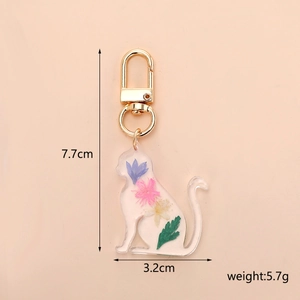 Cat resin keychain with dried flowers and dimensions shown on light beige background