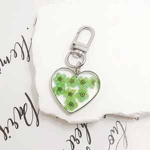 Detail of silver heart keychain featuring natural green dried flowers in clear resin