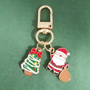 Detail of Christmas keychain with Santa Claus and tree charms in gold-tone metal enamel