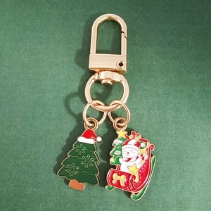 Detail of Christmas snowman and tree charms on a golden alloy metal keychain