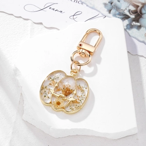 Halloween pumpkin keychain featuring yellow dried flowers and gold leaf in resin
