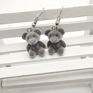 Cute dark grey flocked teddy bear earrings with silver hooks on a white wooden display