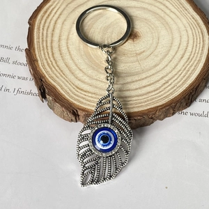 Porte-clés plume vintage avec œil bleu maléfique sur un décor de style bohème ancien