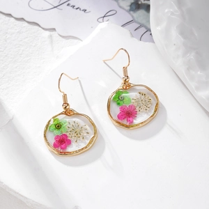 Boucles d'oreilles rondes en résine avec fleurs séchées et crochets dorés sur marbre