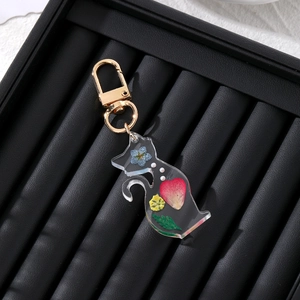 Detailed close-up of resin cat keychain with embedded dried flowers and gold metal clasp
