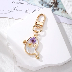 Ghost shaped Halloween keychain with white and purple dried flowers in transparent resin