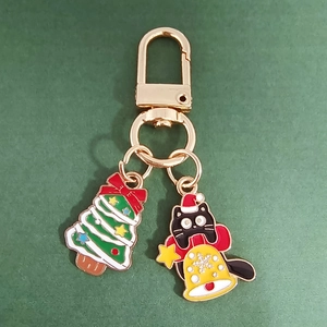 Detail of Christmas cat keychain with enamel tree charm on dark green background