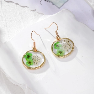 Boucles d'oreilles dorées avec de vraies fleurs séchées vertes et blanches dans de la résine