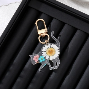 Close-up of cat-shaped resin keychain with real dried flowers on black velvet display box