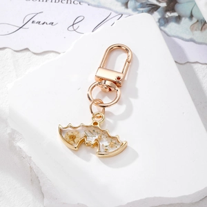 Detailed close-up of a gold bat-shaped keychain with resin-filled dried yellow flowers