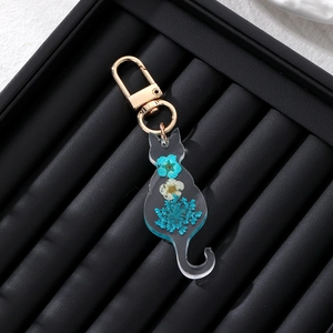 Detailed close-up of resin cat keychain with real blue and white dried flowers