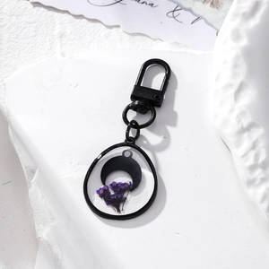 Handmade black moon and purple dried flower resin teardrop keychain on white stone