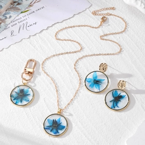 Handmade gold pendant necklace and earring set with blue dried flowers in clear resin
