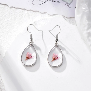 Detail of teardrop resin earrings featuring a real pink dried flower and silver hooks