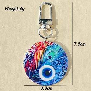 Detail view of Evil Eye and peacock feather pattern on acrylic keychain with dimensions