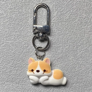 Cute cartoon Corgi resin keychain with silver metal carabiner on a leather background