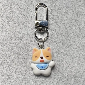 Close-up of cute resin Corgi keychain with a blue heart bib on a grey textured background