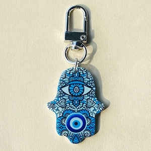 Macro detail of Hamsa Hand keychain with blue evil eye mandala pattern on acrylic
