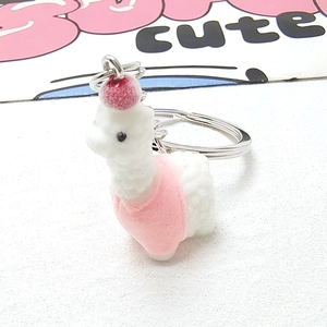 Detailed macro view of cute white flocked alpaca keychain with pink hat and vest accessory