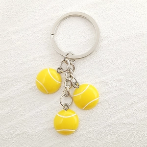 Detailed macro view of three 3D resin yellow tennis ball pendants on a metal keychain