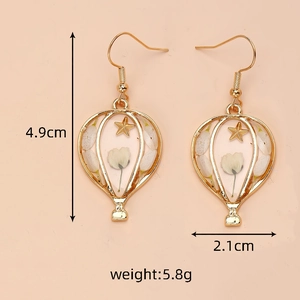 Close-up of hot air balloon earrings with white dried flowers and gold star detail