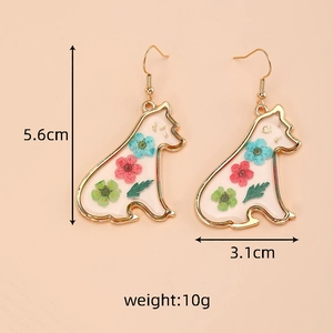 Detail view of handmade resin puppy earrings featuring colorful dried flowers and gold leaf