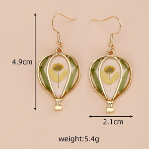 Detail of hot air balloon earrings with yellow dried flowers and gold metal frame