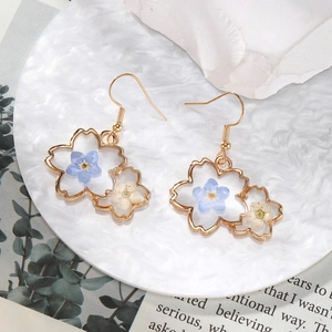 White cherry blossom drop earrings with dried flowers in gold alloy on a water ripple plate