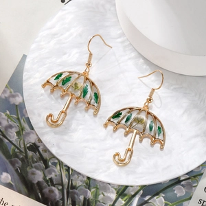Detailed close-up of golden umbrella earrings featuring real green leaves and dried flowers