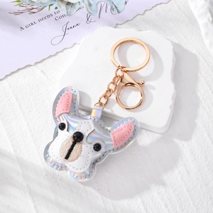 Iridescent bulldog bag charm with gold keychain on a white decorative stone base