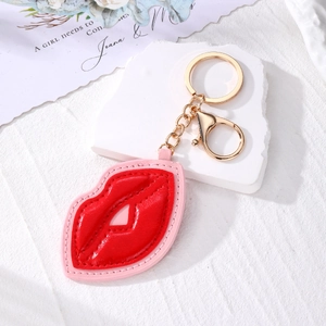 Fashionable red lip leather keychain with gold hardware on a white stone background