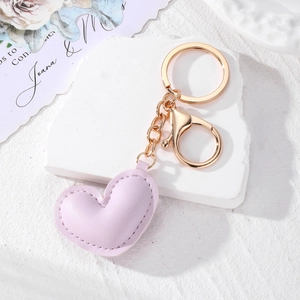 Detailed view of purple leather heart keychain with gold hardware and white stitching