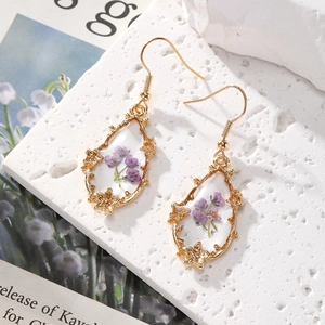 Detail of teardrop earrings with purple dried flowers in gold floral alloy frames