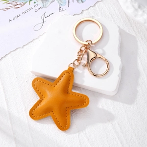 Detail of ginger yellow star leather keychain with fine stitching and gold metal clasp