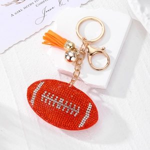 Détail du porte-clés football orange avec strass blancs, pompon et cloche dorée