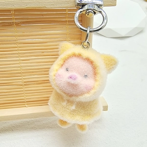 Detail of pink plush pig keychain with yellow hoodie and silver metal lobster clasp