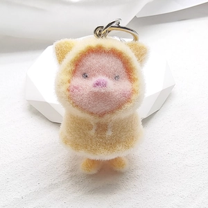 Close-up of cute plush pig keychain with yellow hoodie and soft pink furry texture