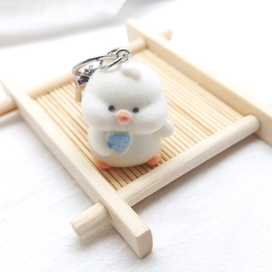 Close-up of cute white flocked chick keychain holding a blue heart on a bamboo tray