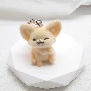 Detail of a cute beige flocked fox keychain with winking face on white geometric stand
