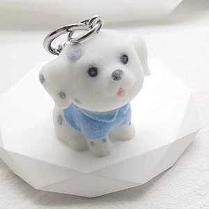 Macro detail of flocked Dalmatian dog charm with black spots and sky blue outfit