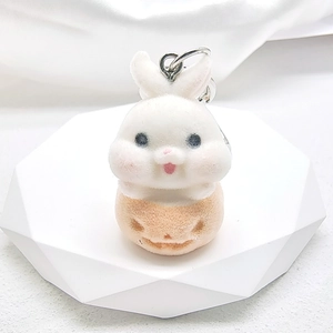 Detailed view of a soft flocked white and orange cartoon rabbit keychain on a stand