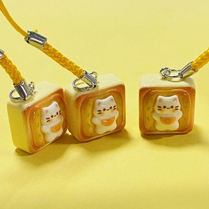 Cute resin cat toast bread charms with yellow braided lanyards on a solid background